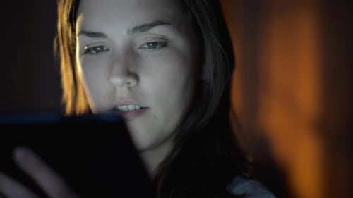 4k video footage of a young woman using a digital tablet late at night