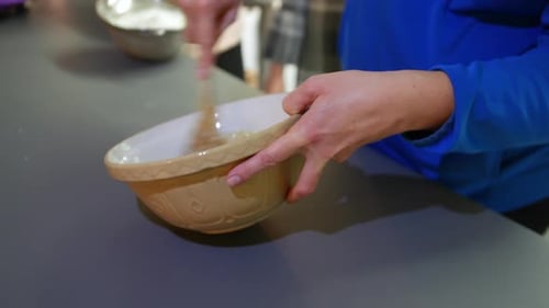 A woman mixing in a bowl cake mixture with flour butter and sugar