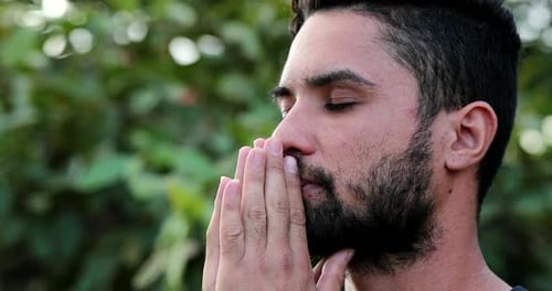 Young man worshiping God outside. Person praying