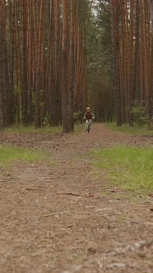 Boy Riding Bike Toward Camera on Forest Path