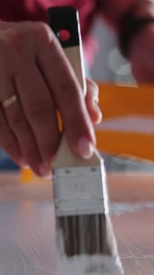 Woman Applies White Paint to Wooden Surface