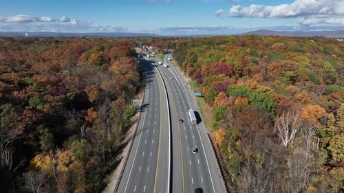 Highway in USA surrounded by colorful fall foliage in Appalachia during autumn. Aerial reverse dolly