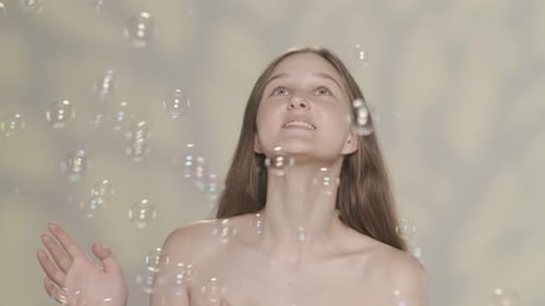 Young Woman Smiles Reaching for Floating Bubbles