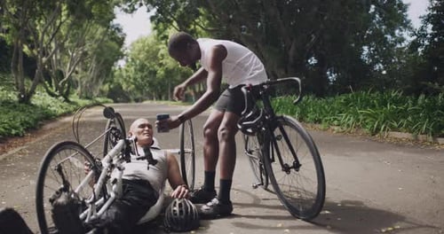 Smiling Cyclist Takes Photo of Fallen Friend