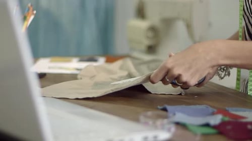 Close up of a Young female fashion designer working at home studio cutting fabric