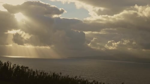 Sunbeams Through Clouds Over Serene Ocean