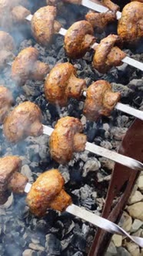 Asar brochetas de champiñones sobre carbón crea una experiencia sabrosa: los champiñones carbonizados y el ahumado