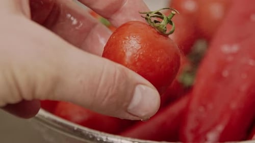 Person Washing a Red Tomato in Kitchen Sink