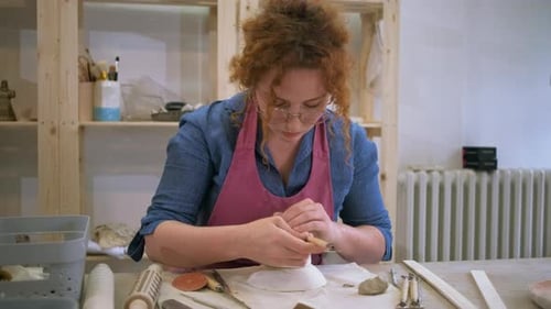 Woman working in pottery studio workshop making bowl from clay.