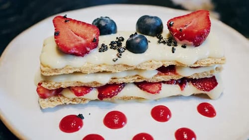 Close up of a Napoleon cake with strawberries and blueberries on a white plate at a cafe