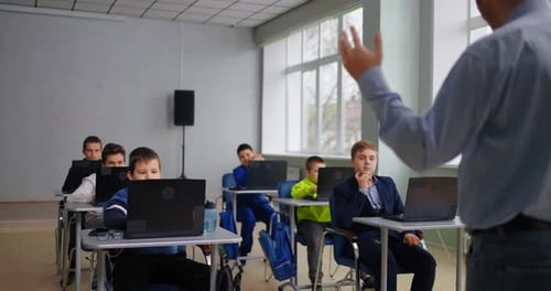 Group Of Teens Boys Studying In School Teacher And Pupils In Modern ComputerBased Classroom