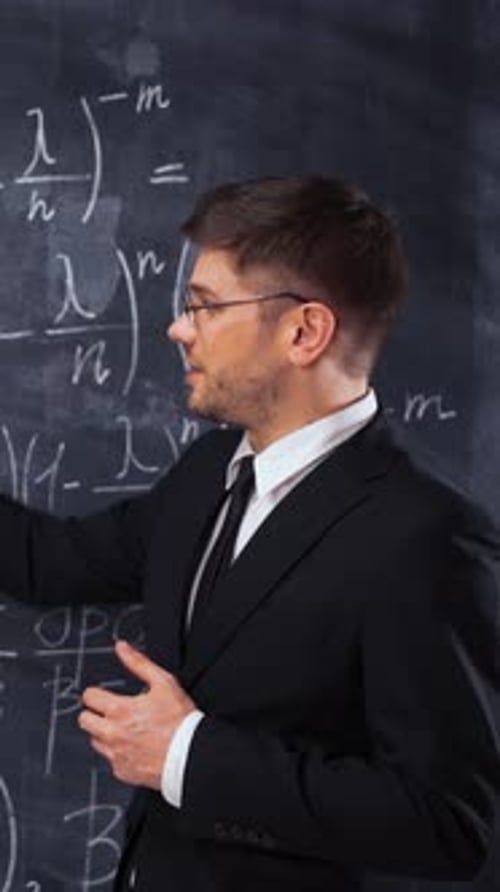 Teacher Explaining Math Equations on Chalkboard