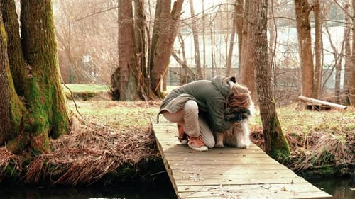Woman Hugging Dog on Bridge in Sunny Forest