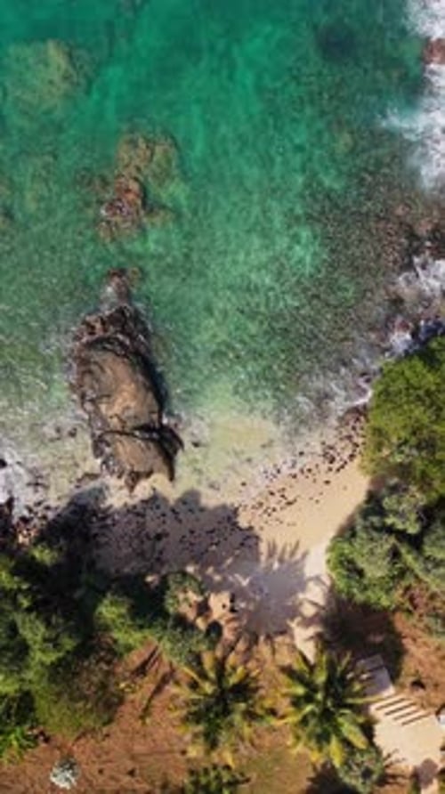 Top down drone shot of beach with rocks in the jungle