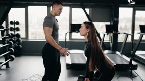 Female Athlete Performing Deadlifts with Personal Trainer in Gym