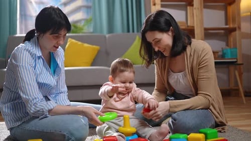 a Two Women on the Living Room Carpetplaying with a Small Child in Colored Children's Toys Close Up