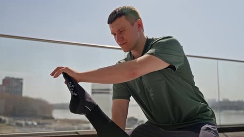Man Stretching Leg of Partner on Rooftop Terrace