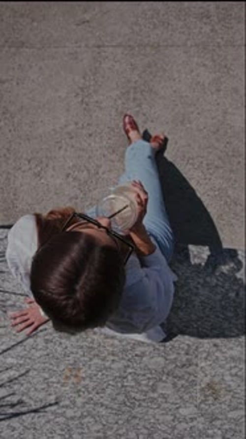Woman Sitting on Street, Relaxing with a Cold Drink