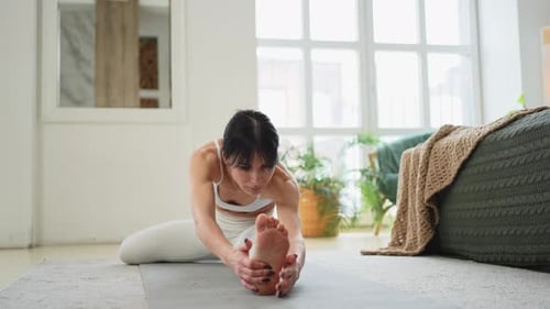 Woman Stretching Hamstrings on Yoga Mat Indoors