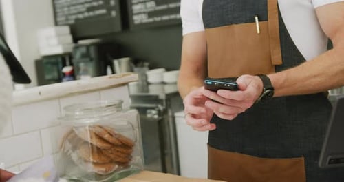 Diverse male barista and female customer paying with credit card in cafe
