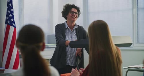 Teacher Lecturing Students in Classroom near American Flag