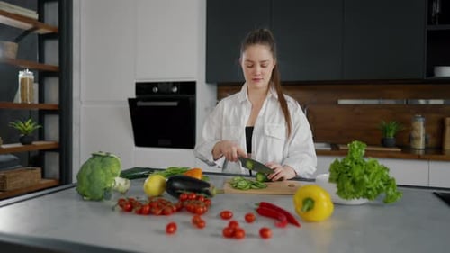 Young Woman Slicing Cucumber in Modern Kitchen