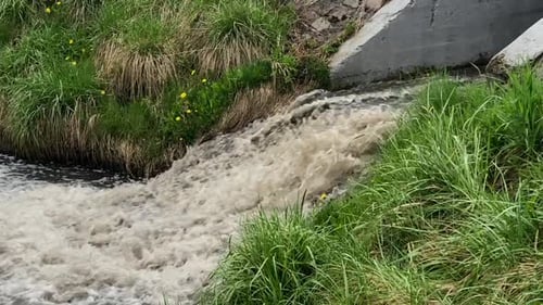 Fast-flowing dirty water gushing into the river through a canal.Environmental pollution.