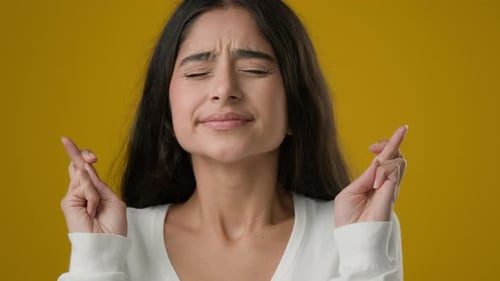 Indian Girl Lady in Yellow Studio Background Crossed Fingers Close Eyes Praying Hope Wish Woman