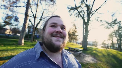 Meditative young chubby man closing eyes in contemplation standing outdoors at park