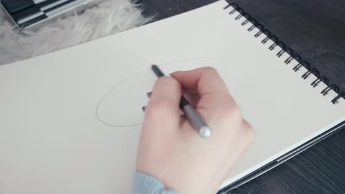 Close up young female caucasian artist hands drawing sketching portrait on paper notebook using char