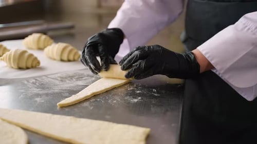 Baker Rolling Croissant Dough in a Commercial Kitchen