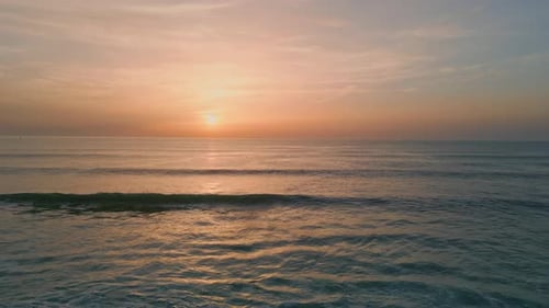 Man silhouette watches pink sunset reflecting on ocean surface at dark cliffs