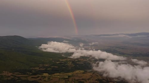 Rainbow Over Clouds and Mountains at Sunset