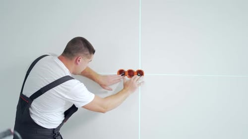 Male worker professional qualified electrician installs electrical outlet in apartment after repair.