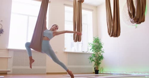 Athletic Woman Doing Aerial Yoga in Indoor Studio
