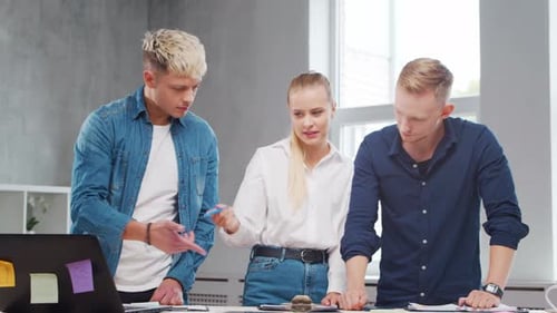 Team of Young Startupers is Working at the Table in the Office Discussing the Strategy and