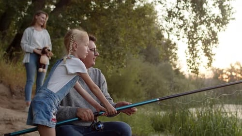 Padre e hija pescando, madre mira detrás