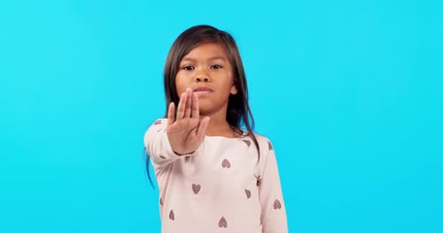 Girl child, hand and stop in studio, face and sign for vote, voice or power to say no by blue