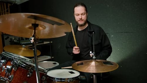 a young male drummer plays a drum kit in a recording studio at a professional musician's rehearsal