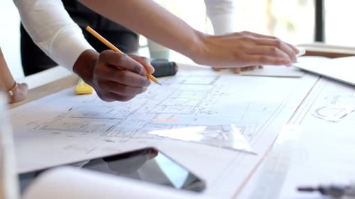 Reviewing architectural blueprints, business professionals collaborating on project plans in office