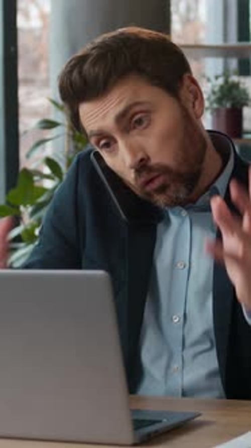 Caucasian Multitasking Businessman Typing Laptop Talking Mobile Phone in Office Professional