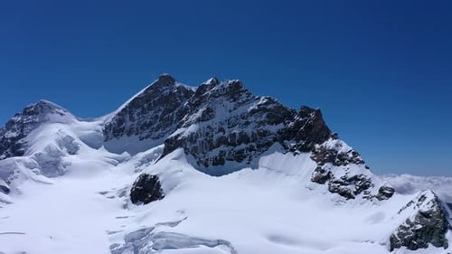 Aerial view of Peaks of a Tall mountain covered in Snow