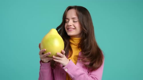 Woman Holding and Kissing a Large Yellow Fruit