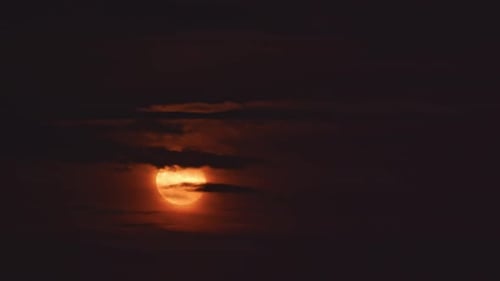 Les nuages du soir flottent sur fond de pleine lune rouge