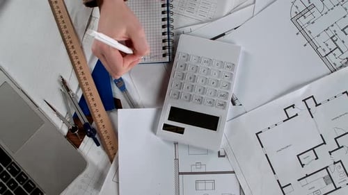 Architect Reviewing Blueprints and Calculating Project Data