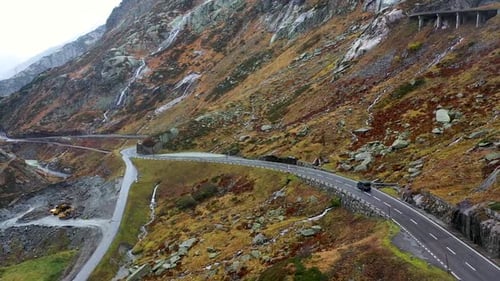 gray camper van driving Grimselpass road in Switzerland in autumn . Aerial view . wet winding road,