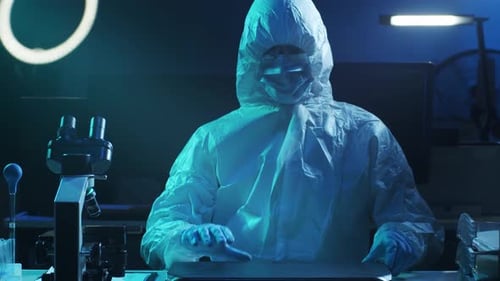 Scientist in Clean Suit Opening Laptop in Lab