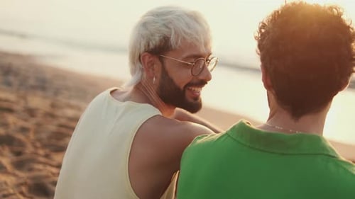 De perto, casal homossexual apaixonado passa tempo juntos sentados na praia ao nascer do sol