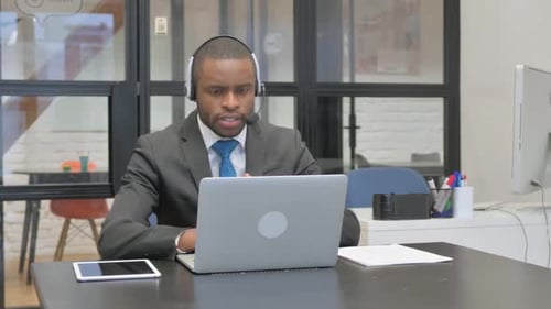 Adult talking on laptop in office environment