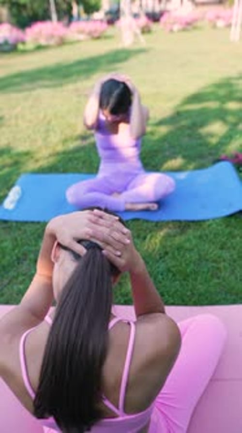A Mother and Her Adult Daughter Both Sporty and Attractive are Practicing Yoga in the Urban Park